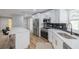 Well-lit kitchen with modern stainless steel appliances, quartz countertops, white cabinets, and wood grain flooring at 2436 Beacon Groves Blvd, Palm Harbor, FL 34683