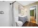 Bathroom with white tiled shower, toilet, and vanity with gray cabinet and dark wood flooring at 320 Tallahassee Ne Dr, St Petersburg, FL 33702