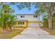 Bright two-story home with a yellow brick facade, white siding, an attached two-car garage and mature landscaping at 320 Tallahassee Ne Dr, St Petersburg, FL 33702