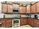 Kitchen featuring dark cabinets, stainless steel appliances, tile backsplash, and granite countertops at 3302 Granite Ridge Loop, Land O Lakes, FL 34638