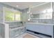 Stunning bathroom with blue tile, double sink vanity, soaking tub, and a large mirror at 4202 Deepwater Ln, Tampa, FL 33615