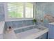 Beautiful bathroom featuring a soaking tub with marble trim and shuttered window for natural light at 4202 Deepwater Ln, Tampa, FL 33615