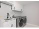 Well-lit laundry room with gray front-loading washer and dryer plus white cabinetry at 4202 Deepwater Ln, Tampa, FL 33615