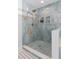 Walk-in shower featuring blue tile surround, bronze fixtures and mosaic tiled floor and shelving at 4202 Deepwater Ln, Tampa, FL 33615
