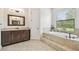 Bathroom with a tub, wooden vanity, granite countertops, and a large window at 4608 Scott Rd, Lutz, FL 33558
