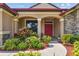 Inviting front entrance with a bright red door, colorful landscaping, and stone accents at 4608 Scott Rd, Lutz, FL 33558