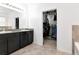 Bathroom featuring double sinks, granite countertop, dark cabinets, and walk-in closet at 5446 Suncatcher Dr, Wesley Chapel, FL 33545