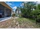 View of covered patio and stone fire pit in a backyard with black metal fence at 5925 Sweet William Ter, Land O Lakes, FL 34639