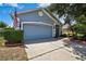 Charming home featuring a two-car garage and a manicured front lawn with landscaping at 5925 Sweet William Ter, Land O Lakes, FL 34639