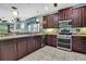 Updated kitchen with stainless steel appliances, dark wood cabinets, tile flooring, and ample counter space at 5925 Sweet William Ter, Land O Lakes, FL 34639