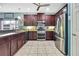Spacious kitchen featuring stainless steel appliances, dark cabinets, tile floors, and an open layout at 5925 Sweet William Ter, Land O Lakes, FL 34639