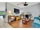 Comfortable living room with hardwood floors, featuring a TV, ceiling fan, and a comfortable blue sofa at 5925 Sweet William Ter, Land O Lakes, FL 34639