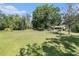 View of a spacious backyard featuring a large lawn, mature trees, and property fencing at 5960 Boyette Rd, Wesley Chapel, FL 33545