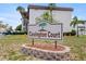 Welcoming entrance to Covington Court with a beautifully maintained sign surrounded by lush landscaping and swaying palm trees at 6370 1St N St # 202, St Petersburg, FL 33702