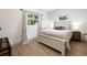 Bright bedroom with a white wood bed, wood-look floors, and curtains framing the window at 6618 12Th N St, St Petersburg, FL 33702
