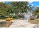 Landscaped front yard with mature trees and a curved driveway leading to an attached garage at 6618 12Th N St, St Petersburg, FL 33702