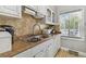 The kitchen features a stainless-steel sink, tile countertops and backsplash, and white cabinets at 7523 Pitch Pine Cir # 184, Tampa, FL 33617