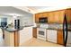 Open concept kitchen with modern appliances, wood cabinets, and breakfast bar at 7625 Sun Island S Dr # 304, South Pasadena, FL 33707