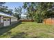 Large, grassy backyard with wooden privacy fence, mature trees, and detached garage at 816 9Th Sw Ave, Largo, FL 33770