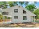 Bright home exterior with balcony, modern windows, and white siding, surrounded by lush trees at 8521 N 29Th St, Tampa, FL 33604