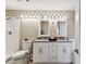 Bathroom features white cabinetry, double sinks, granite counters, decorative lighting, and walk-in shower at 8601 Chadwick Dr, Tampa, FL 33635