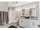 Bathroom featuring double sinks, granite countertop, white cabinets, a walk-in shower, and contemporary lighting at 8601 Chadwick Dr, Tampa, FL 33635