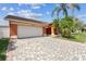 Single-story home featuring a brick driveway, lush palm trees and a two-car garage at 8601 Chadwick Dr, Tampa, FL 33635