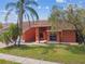 Exterior front view of home featuring colorful plants, grass, mature trees, and architectural design at 8601 Chadwick Dr, Tampa, FL 33635