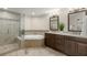 Bathroom featuring dual sink vanity, a soaking tub, and a glass enclosed walk-in shower at 9201 Captiva Cir, St Pete Beach, FL 33706