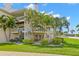 Low-angle exterior view of a multi-story condo with a lush lawn and landscaping at 9201 Captiva Cir, St Pete Beach, FL 33706
