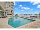 Inviting community pool with lounge chairs, lush landscaping, and beautiful views of the waterfront and surrounding buildings at 9201 Captiva Cir, St Pete Beach, FL 33706