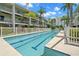 Community outdoor swimming pool with palm trees and a white fence at 9201 Captiva Cir, St Pete Beach, FL 33706