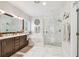 Bright bathroom with marble counters, brown cabinets, large tub, glass enclosed shower, and luxurious finishes at 925 Monticello N Blvd, St Petersburg, FL 33703