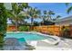 Backyard pool featuring a unique sun shelf with white lounge chairs surrounded by lush landscaping at 925 Monticello N Blvd, St Petersburg, FL 33703