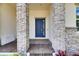 Inviting front entrance featuring a blue door flanked by stone pillars and brick paving at 1028 Signet Dr, Apollo Beach, FL 33572