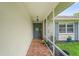 Covered front porch with brick flooring, screened walls and a decorated front door at 1038 Shenandoah Ln, Spring Hill, FL 34606