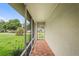Screened front porch with brick flooring and view of manicured front yard at 1038 Shenandoah Ln, Spring Hill, FL 34606