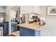 Bright kitchen with white cabinets, stainless steel appliances, blue kitchen island and breakfast bar seating at 1038 Shenandoah Ln, Spring Hill, FL 34606
