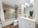 Bright bathroom featuring tub-shower combo, modern vanity, framed mirror, and wood look floors at 105 4Th Ne Ave # 426, St Petersburg, FL 33701