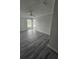 Neutral bedroom featuring gray wood-look floors, white walls, a ceiling fan, and bright windows at 1107 Queen Anne Dr # C, Palm Harbor, FL 34684
