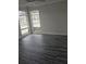 Bright bedroom with gray wood-look floors, large windows, and neutral walls at 1107 Queen Anne Dr # C, Palm Harbor, FL 34684