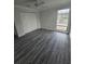 Bedroom featuring gray wood-look floors, ceiling fan, closet, large window, and neutral walls at 1107 Queen Anne Dr # C, Palm Harbor, FL 34684