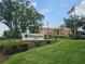 Highland Lakes Clubhouse surrounded by lush landscaping and the American flag waving in the background at 1107 Queen Anne Dr # C, Palm Harbor, FL 34684