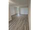 Bright living room featuring gray wood-look floors, white walls, and a glass-paneled front door at 1107 Queen Anne Dr # C, Palm Harbor, FL 34684