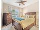 Cozy bedroom features wood furniture, ceiling fan, and large window with neighborhood view at 11429 Drifting Leaf Dr, Riverview, FL 33579