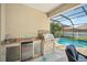 Outdoor kitchen boasts a stainless grill, sink, mini fridge, and stone counter perfect for poolside entertaining at 11429 Drifting Leaf Dr, Riverview, FL 33579