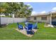 Backyard with manicured lawn and a cozy fire pit area surrounded by four blue Adirondack chairs for relaxing outdoor gatherings at 13514 Oval W Dr, Largo, FL 33774