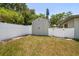 Backyard featuring a storage shed surrounded by a white fence and lush trees, providing both functionality and privacy at 13514 Oval W Dr, Largo, FL 33774