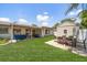 Spacious backyard featuring a covered patio with outdoor seating, a dining area, and a well-maintained lawn at 13514 Oval W Dr, Largo, FL 33774