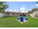 Wide backyard with lush grass, a fire pit with seating, and a covered patio with a comfortable outdoor seating area at 13514 Oval W Dr, Largo, FL 33774